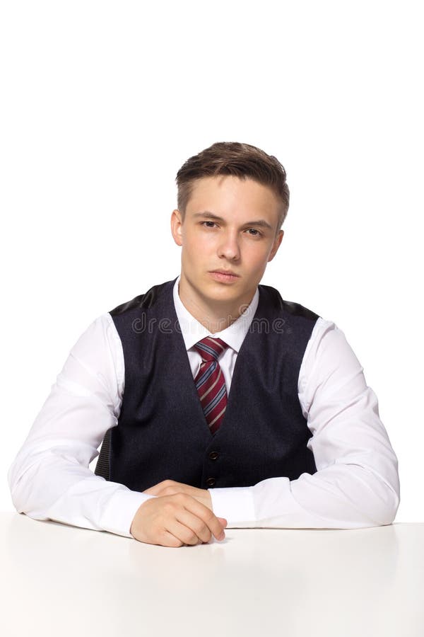 Случайный молодой бизнесмен работая в офисе, сидящ на столе, думающ о том, что-то, смотря камеру стоковые фотографии rf